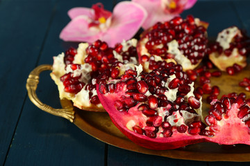 Pomegranate seeds on metal tray on wooden table, closeup