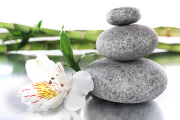 Fototapeta na wymiar Stack of spa stones with flower and bamboo sticks isolated on white
