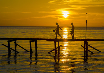 Sunset with boy and jetty silhouette