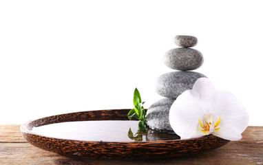 Obraz na płótnie Canvas Spa stones with orchid and bamboo in wooden tray with water isolated on white