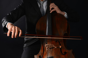 Man playing on cello on dark background © Africa Studio
