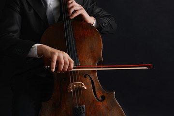 Man playing on cello on dark background