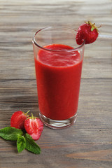 Glass of strawberry smoothie with berries on wooden table close up