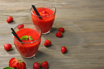 Glasses of strawberry smoothie with berries on wooden table close up