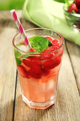 Glass of strawberry juice with berries on table close up