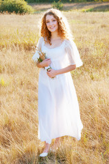Fototapeta na wymiar Woman with curly golden hair smiling standing in the field