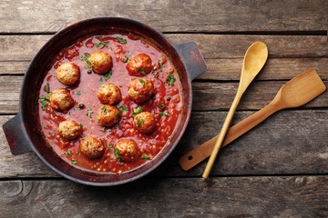 Pan with meat balls in tomato sauce, on wooden background