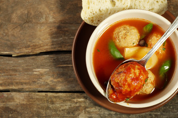Tomato soup with meat balls on wooden spoon on wooden background