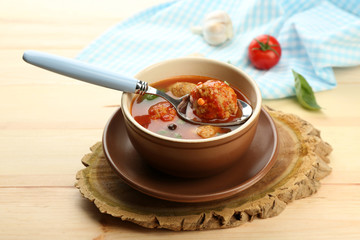 Tomato soup with meat balls on wooden spoon on wooden background