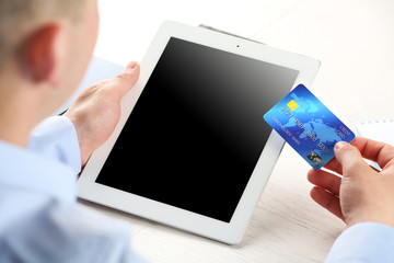 Man holding credit card and tablet on workplace background
