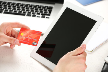 Man holding credit card and tablet on workplace background