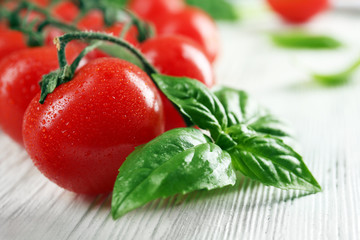 Cherry tomatoes with basil on wooden table close up