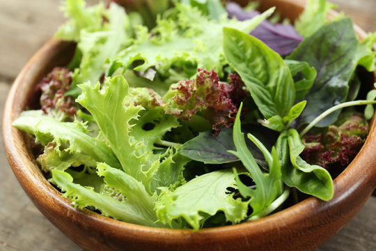 Fresh mixed green salad in bowl close up