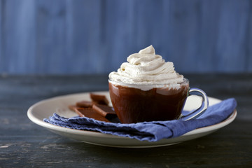 Cup of coffee with cream on color wooden background