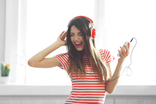 Woman listening music in headphones on windowsill background