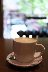 Cup of latte coffee on wooden table in cafe
