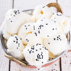 Cream white, ice cream balls in a metal authentic bowl,with black sesame seeds.selective focus