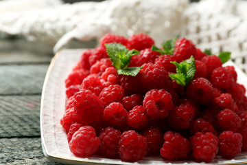 Sweet raspberries on plate on wooden  background
