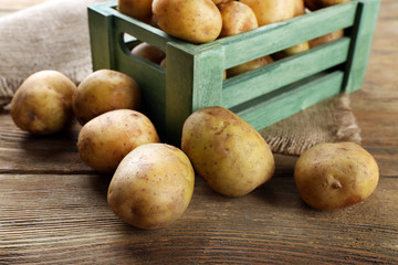 Young potatoes in crate on table close up