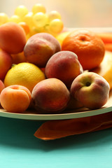 Heap of fresh fruits on tray on wooden table close up