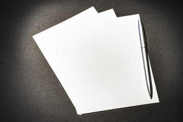 Pen and paper on a leather mat on top of a wooden table