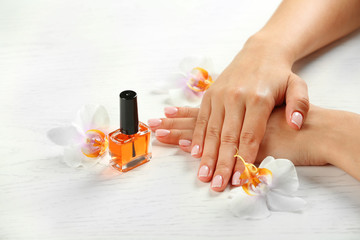 Woman hands with french manicure and orchid flowers on wooden table close-up