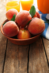 Ripe peaches and juice in glass on wooden background