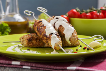 Barbecued kofta - kebeb topped with sauce with vegetables on a p