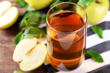 Glass of apple juice on wooden table, closeup