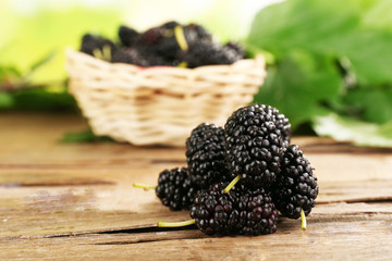 Fresh mulberry in wicker basket on wooden table, closeup