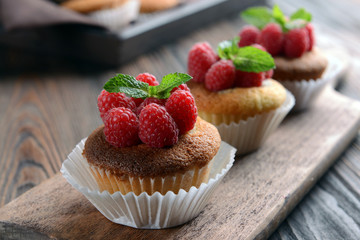 Delicious cupcakes with berries and fresh mint on wooden table close up