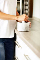Woman hands with mortar with herbs on bright background