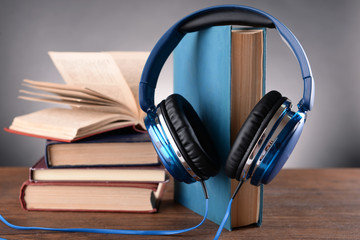 Obraz na płótnie Canvas Books and headphones as audio books concept on grey background