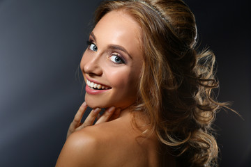 Fototapeta premium Beautiful woman with curly long hair on dark background