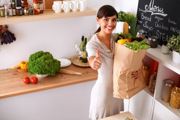 Young woman holding grocery shopping bag with vegetables