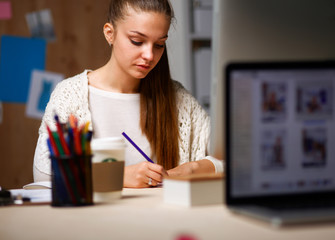 Young woman working in office, sitting at desk