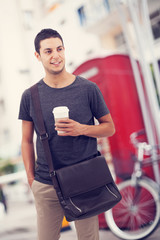 Man walking and drinking coffee in city