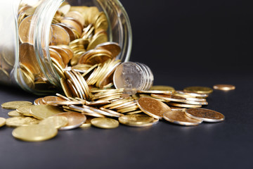 Glass jar with coins on dark background