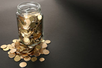 Glass jar with coins on dark background
