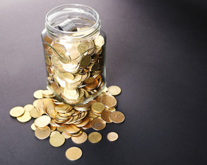 Glass jar with coins on dark background