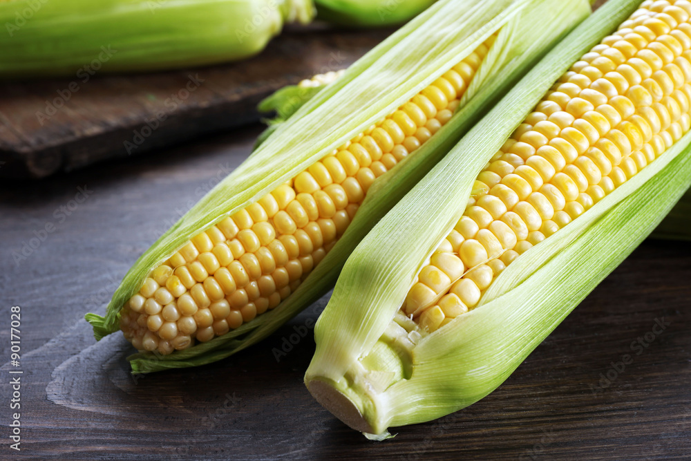 Sticker fresh corn on cobs on wooden table, closeup