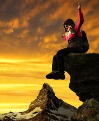 Papier Peint photo Cervin Girl sitting on a rock, in the background Matterhorn at sunset