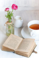 Tow pink ranunculus and old opening book