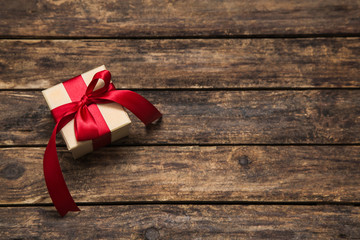 Ein rotes Geschenk mit Schleife auf Holz Hintergrund.