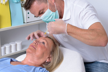 Obraz na płótnie Canvas Male Clinician Injecting on Face of a Woman