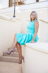 beautiful girl in a turquoise dress posing on the steps, outdoor