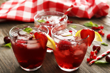 Glasses of berry juice on wooden table, closeup