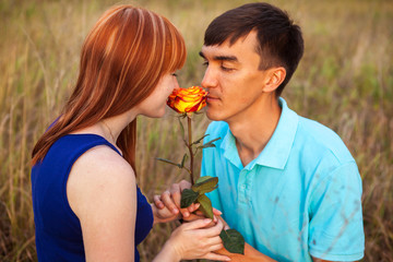 Fototapeta premium young couple in love looking at the flower in the park, close-up