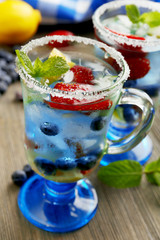 Glasses of berries juice on wooden table, closeup