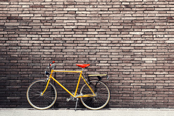 Naklejka premium Retro bicycle on roadside with vintage brick wall background